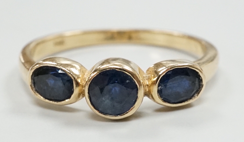 A modern 585 yellow metal and three stone sapphire set ring, size O, gross weight 2.4 grams.